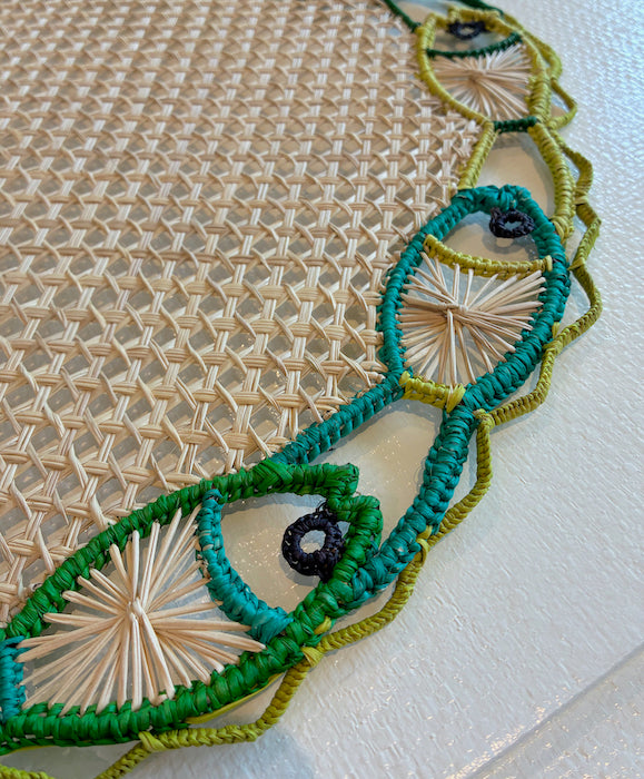Close-up of the Mercedes Salazar Fish Dance Placemat featuring a beige lattice center and a vibrant stitched border in green, blue, and yellow.