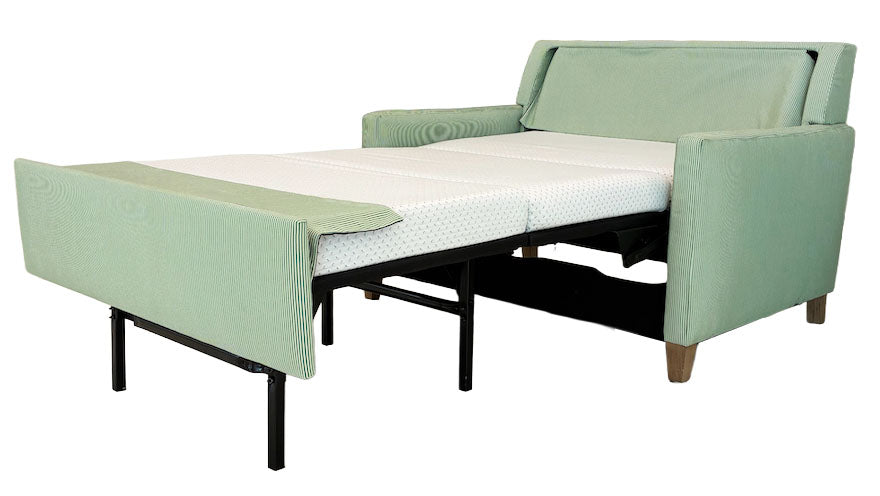 The Lee Industries Twin XL Sleeper Sofa, upholstered in light green with wooden legs, is displayed extended as a twin XL bed with a white mattress.