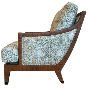 Side view of the St. Germain Lounge Chair by McGuire Furniture, featuring a wooden frame with angled legs and upholstered frame, plus light-patterned cushions inspired by French floral and seashell motifs.