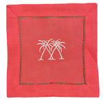 The Coastal Cocktail Napkin Set by Pink House Mustique features red linen napkins with two white palm trees embroidered at the center and a decorative stitched border, perfect for adding a coastal touch to any gathering.