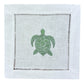 The Coastal Cocktail Napkin Set by Pink House Mustique features white linen napkins with a green embroidered turtle and cutwork hemstitch—ideal for adding seaside charm to your table.