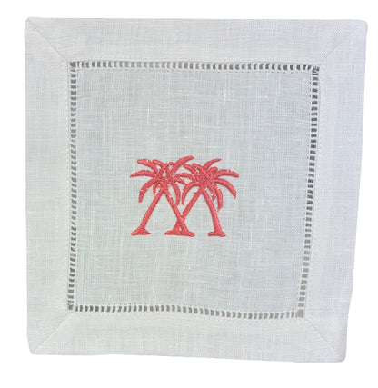 The Coastal Cocktail Napkin Set by Pink House Mustique features white linen napkins with embroidered pink palm trees at the center and a coastal-inspired hemstitch border.