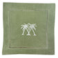 The Pink House Mustique Coastal Cocktail Napkin Set features coastal green linen napkins with two white embroidered palm trees in the center and a decorative stitched border.