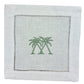 The Coastal Cocktail Napkin Set by Pink House Mustique features white linen napkins with two green palm trees embroidered in the center and a decorative openwork hem, adding a refined coastal touch.