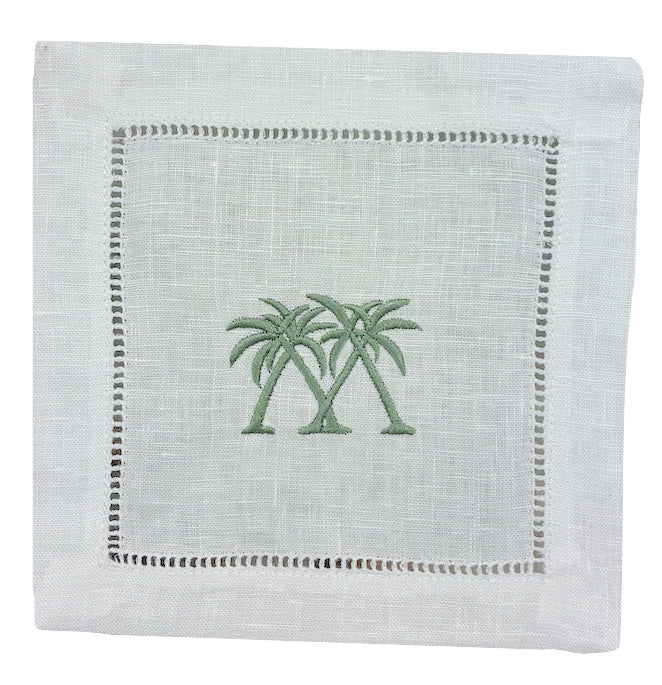 The Coastal Cocktail Napkin Set by Pink House Mustique features white linen napkins with two green palm trees embroidered in the center and a decorative openwork hem, adding a refined coastal touch.