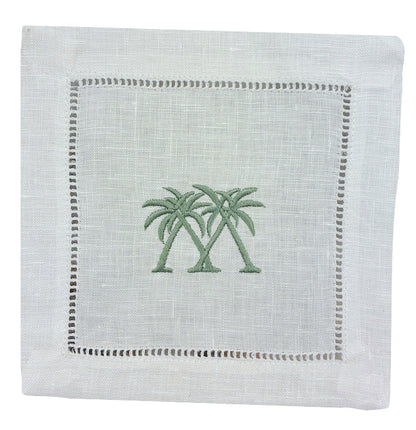 The Coastal Cocktail Napkin Set by Pink House Mustique features white linen napkins with two green palm trees embroidered in the center and a decorative openwork hem, adding a refined coastal touch.