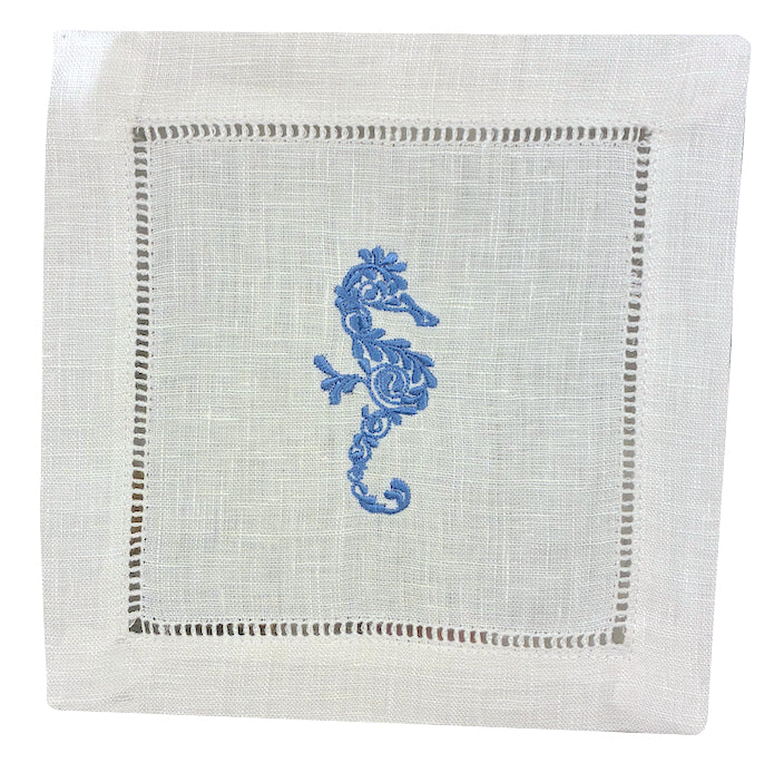 Add coastal charm to your table with the Coastal Cocktail Napkin Set by Pink House Mustique—white linen napkins featuring a blue embroidered seahorse and decorative cutwork border.