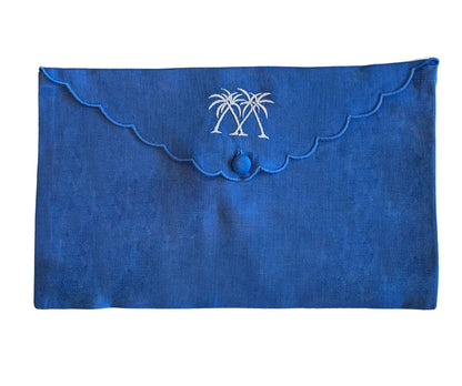 The Pink House Mustique Linen Envelope Pouch Collection features blue linen pouches with scalloped edges, button closure, and two white palm tree embroideries for a coastal touch.