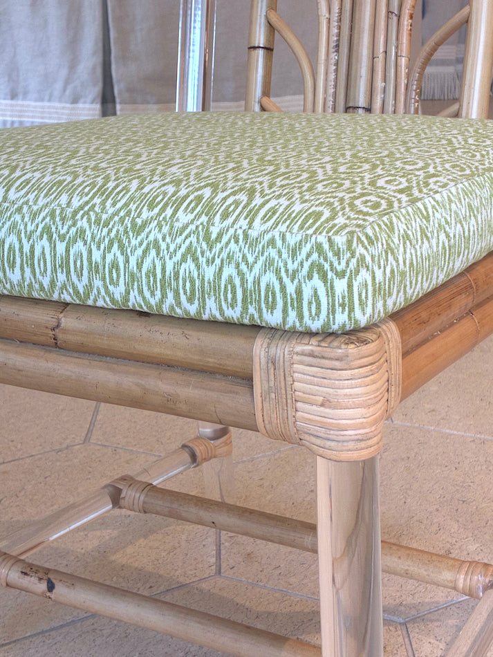 Close-up of the Sea Cliff Side Chair, Amala Vert by Associated Design, with an acrylic and bamboo frame and a custom green Amala Ikat cushion, set on a tiled floor.