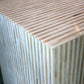 A close-up of the Bojay Stripe Side Table, featuring alternating light and dark beige horizontal stripes that emphasize its artisanal craftsmanship.
