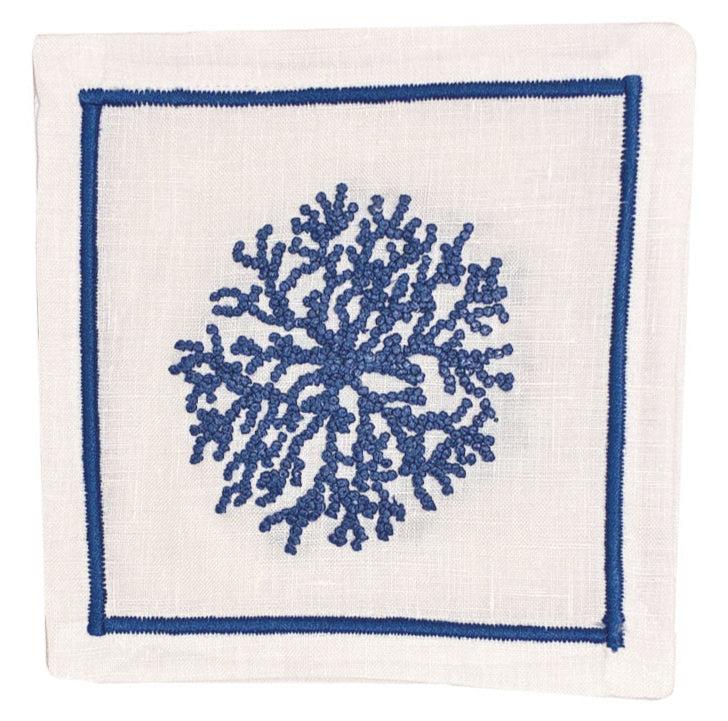 The Haute Home Sea Sponge Coaster Set features white linen coasters with a blue hand-embroidered coral motif at the center, outlined by a blue rectangular border.