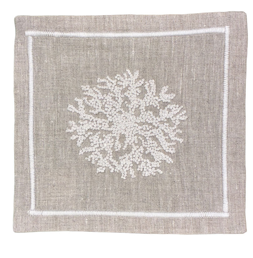 The Haute Home Sea Sponge Coaster Set features square beige linen coasters with white hand-embroidered coral designs and stitched borders—perfect for pairing with matching linen napkins.