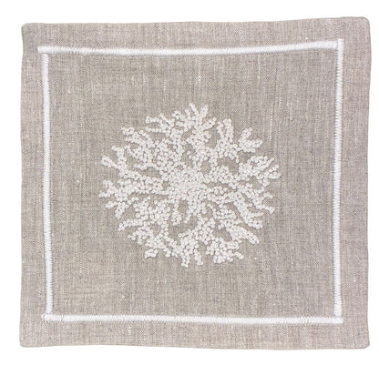 The Haute Home Sea Sponge Coaster Set features square beige linen coasters with white hand-embroidered coral designs and stitched borders—perfect for pairing with matching linen napkins.