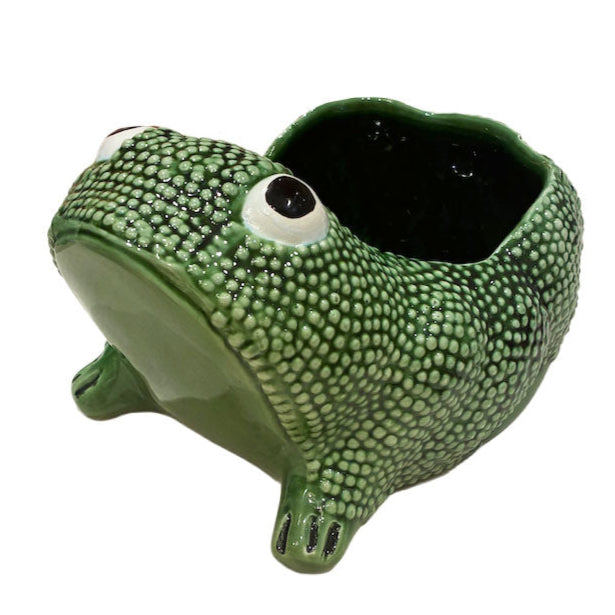 The Ceramic Frog Collection by Jean Roger Paris features a green ceramic planter shaped like the brand’s iconic frog, with an open back cavity for holding small plants or items.