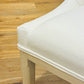 Close-up of the Maurice Dining Chair by Sherrill/Mr & Mrs Howard, showcasing elegant white upholstery and wooden legs on a light brown floor—ideal for stylish, comfortable seating.
