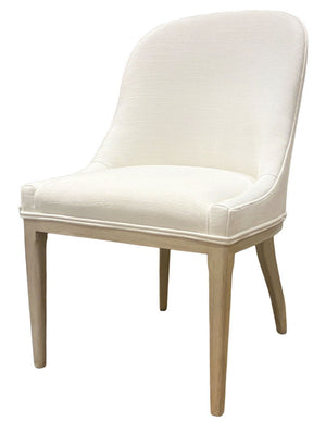 The Maurice Dining Chair by Sherrill/Mr & Mrs Howard features white upholstery, a curved backrest, and light wooden legs, combining comfort and elegance, set against a plain background.