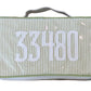 The Walker Valentine Handled Brush and Makeup Case features green and white stripes, a handle, and “33480” embroidered in white—ideal for travel and organizing your essentials.