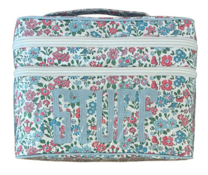 The Walton Travel Case by Walker Valentine is a rectangular organizer with a floral pattern and "STUFF" in bold on the front. Double zippers open to spacious compartments for essentials.