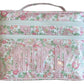 The Walton Travel Case by Walker Valentine features a floral pattern with pink and green flowers, double zippers, two spacious compartments, and "MAKE UP" in bold pink letters—ideal for stylish travel.