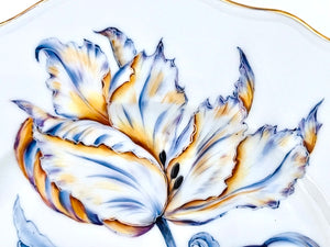 Close-up of the Botanical Treasures Salad Plate VI by Anna Weatherley, a white porcelain plate with intricate hand-painted yellow, blue, and purple floral details and a gold rim.