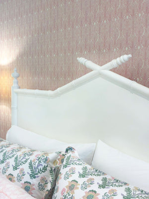 The Bambu King Bed by Sherrill/Mr & Mrs Howard features a white wooden headboard with crossed posts, standing out against pink patterned wallpaper and floral bedding for a timeless solid wood look.