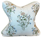 The Flax Field Flower with Leaf Trim Pillow by Hive Custom Pillows features a botanical floral pattern in green, blue, yellow, and brown on a white background, finished with green trim for a touch of luxury.
