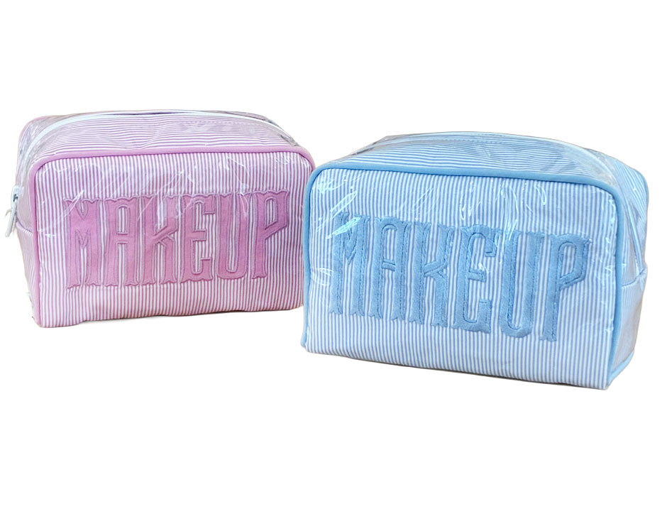 The Walker Valentine Small Milan Cosmetic Case features "MAKEUP" embroidery, comes in pink and blue, and is covered in clear plastic—ideal as a stylish beauty organizer or travel makeup case.