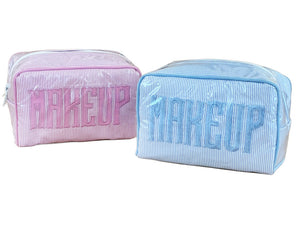 The Walker Valentine Small Milan Cosmetic Case features "MAKEUP" embroidery, comes in pink and blue, and is covered in clear plastic—ideal as a stylish beauty organizer or travel makeup case.