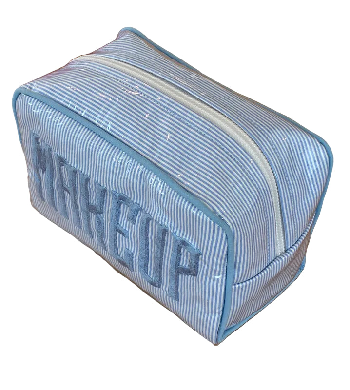 The Walker Valentine Small Milan Cosmetic Case features blue and white stripes, a top zipper, and "MAKEUP" embroidery—perfect for organizing beauty essentials at home or on the go.