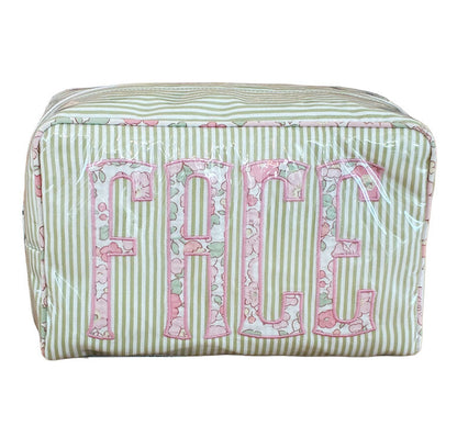The Walker Valentine Large Milan Cosmetic Case, "FACE," is a rectangular striped travel makeup bag with a floral pattern and bold pink lettering—ideal as a beauty organizer for your essentials.