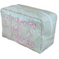 The Walker Valentine Large Milan Cosmetic Case, "FACE," features green and white stripes, a zip closure, and bold pink floral letters—ideal as a travel makeup bag or cosmetic organizer.
