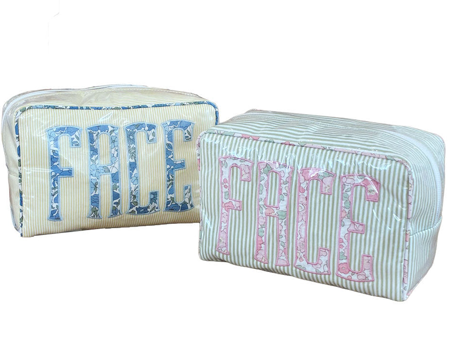 Two Walker Valentine Large Milan Cosmetic Cases with "FACE" embroidery—one in blue, one in pink—feature striped fabric and are perfect as beauty organizers or travel makeup bags.