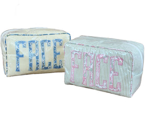Two Walker Valentine Large Milan Cosmetic Cases with "FACE" embroidery—one in blue, one in pink—feature striped fabric and are perfect as beauty organizers or travel makeup bags.