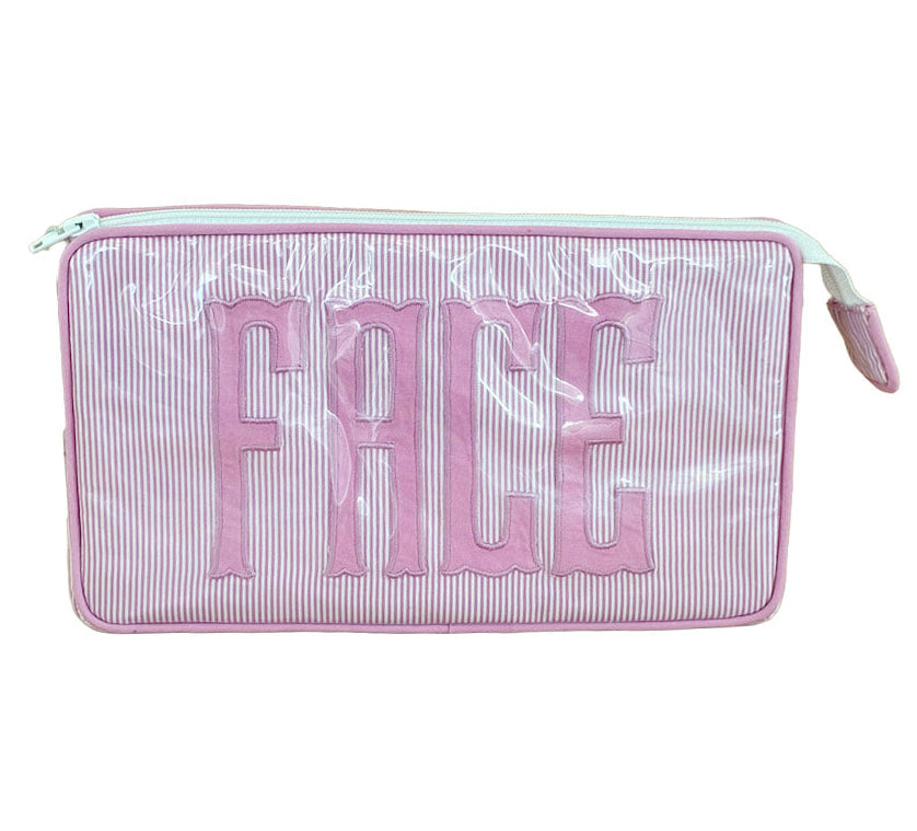 The Small Helen Cosmetic Case "FACE" by Walker Valentine features pink and white stripes, a zippered closure, and "FACE" embroidered in bold pink letters—your perfect travel makeup bag.