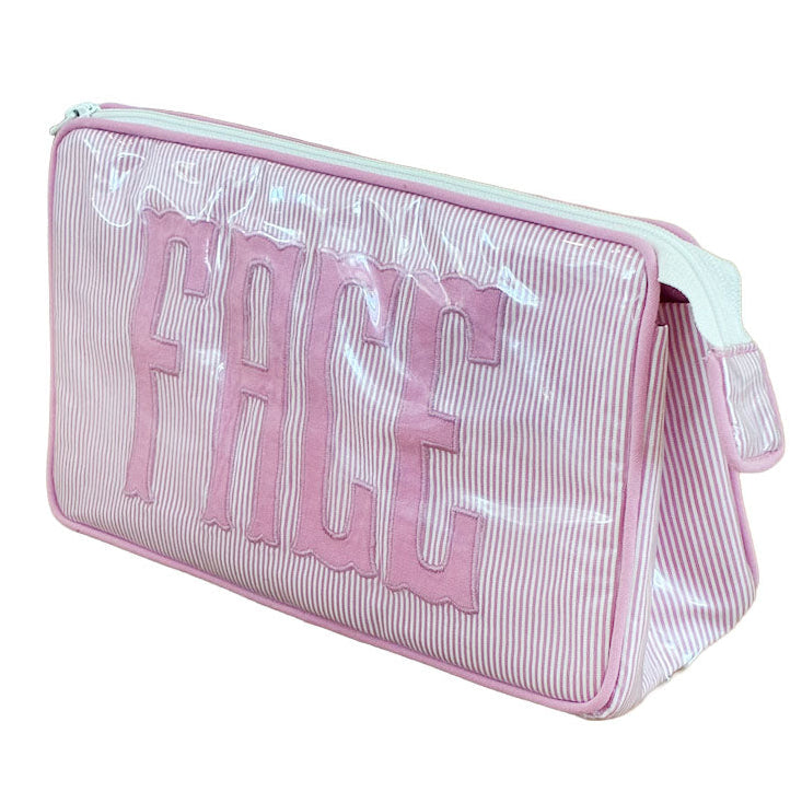 The Walker Valentine Small Helen Cosmetic Case features pink and white stripes, a transparent cover, and "FACE" in bold pink letters—perfect for stylish, organized travel.