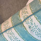 A close-up of the Andalus Mineral Lumbar Pillow by Hive Custom Pillows, showcasing its blue and white floral and scalloped design on a textured gray surface.