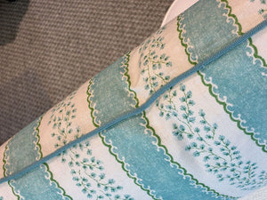 A close-up of the Andalus Mineral Lumbar Pillow by Hive Custom Pillows, showcasing its blue and white floral and scalloped design on a textured gray surface.