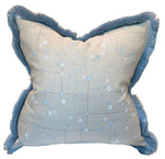 The Klimt Grid Pillow with Sky Brush Fringe by Associated Design features light beige fabric with a blue abstract dot pattern and blue fringed edges—a luxurious decorative accent for any space.