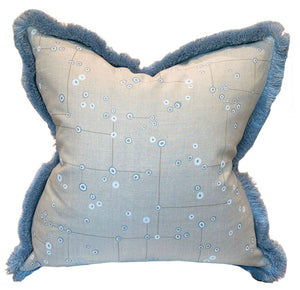 The Klimt Grid Pillow with Sky Brush Fringe by Associated Design features light beige fabric with a blue abstract dot pattern and blue fringed edges—a luxurious decorative accent for any space.