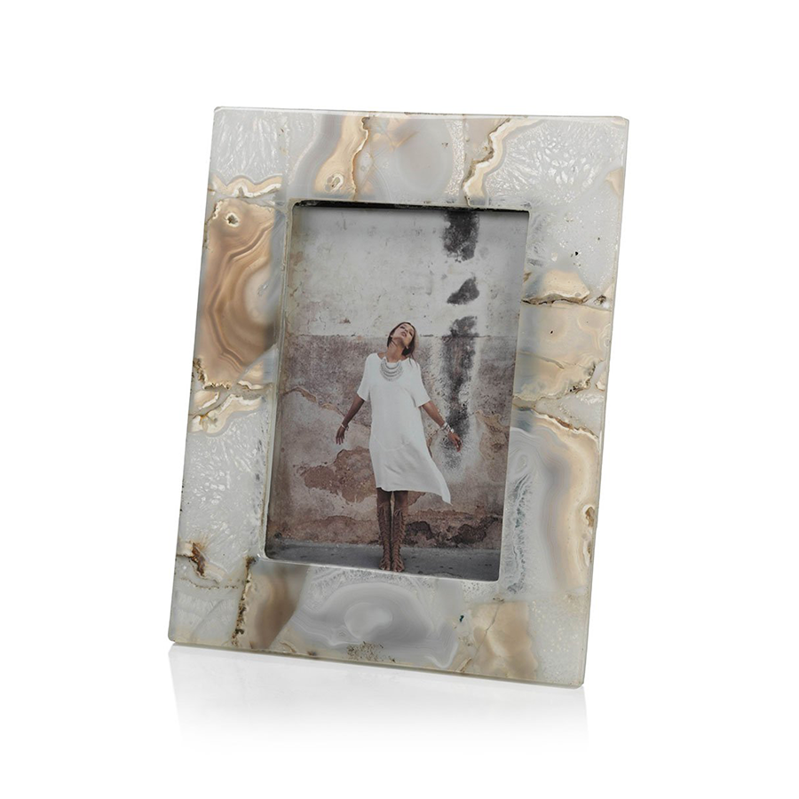 The Zodax Preto Agate Frame features a rectangular agate stone with a marble pattern, displaying a woman in a white dress standing against a textured wall.