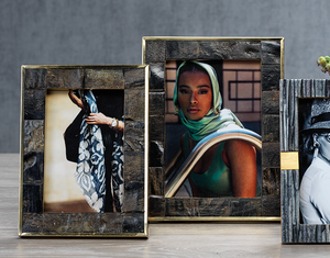 Three Natural Horn with Brass Trim frames by Zodax sit on a table, each showing portraits of women—two in color, one in black and white. The frames’ gold accents lend a sophisticated touch to their elegant design.