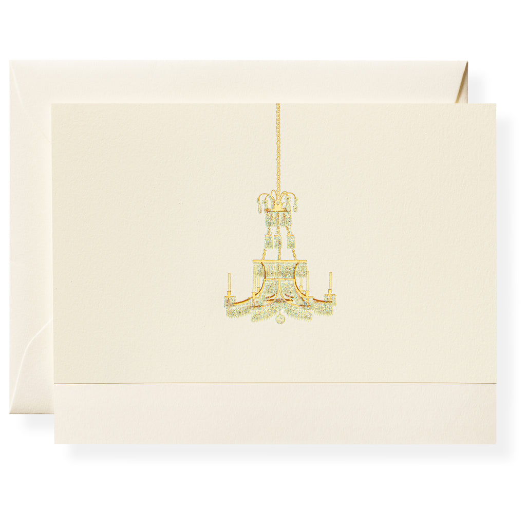 The Karen Adams Dolce Vita Card Set features a cream-colored, hand-embellished card with a gold chandelier illustration and a matching envelope—an elegant hostess gift.