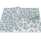 A folded blanket from Matouk’s Iconic Leopard Sky Tabletop Collection, featuring a light blue and white leopard print on a white background.
