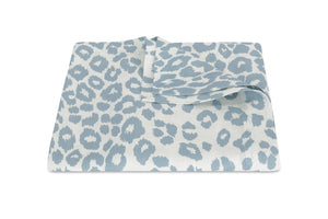 The Matouk Iconic Leopard Sky Tabletop Collection features a striking blue and white leopard print elegantly set against a crisp white linen background.