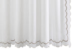 Matouk’s India Pique Shower Curtain Collection features a white diamond pique panel with scalloped edges and beige trim, accented by double-scallop embroidery and crafted from a cotton blend fabric, shown hanging vertically.