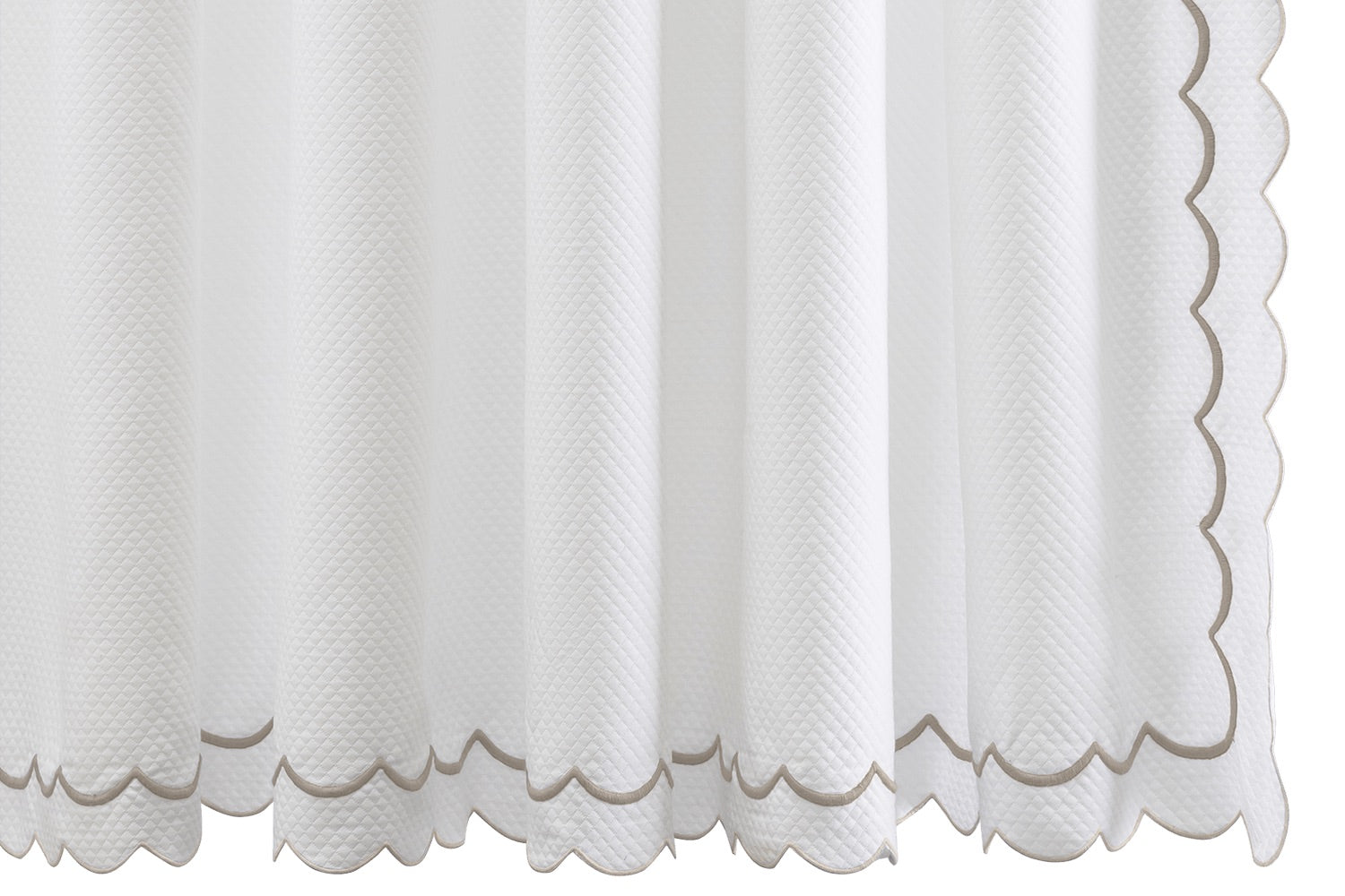 Matouk’s India Pique Shower Curtain Collection features a white diamond pique panel with scalloped edges and beige trim, accented by double-scallop embroidery and crafted from a cotton blend fabric, shown hanging vertically.