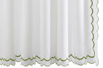 The India Pique Shower Curtain Collection by Matouk showcases white textured curtains adorned with a delicate double-scallop green trim along the bottom and right edge, featuring signature India embroidery, displayed against a white background.