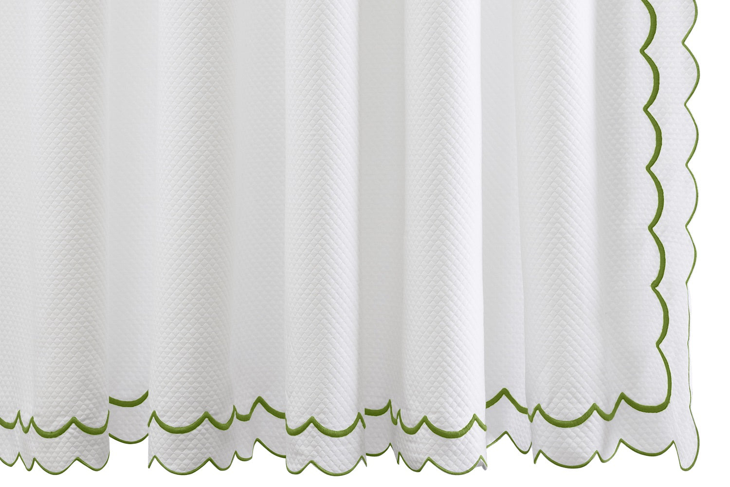 The India Pique Shower Curtain Collection by Matouk showcases white textured curtains adorned with a delicate double-scallop green trim along the bottom and right edge, featuring signature India embroidery, displayed against a white background.