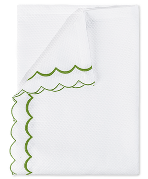 A folded white diamond pique napkin from the Matouk India Pique Bedding Collection in Grass, featuring green double-scallop embroidery along the textured edges.