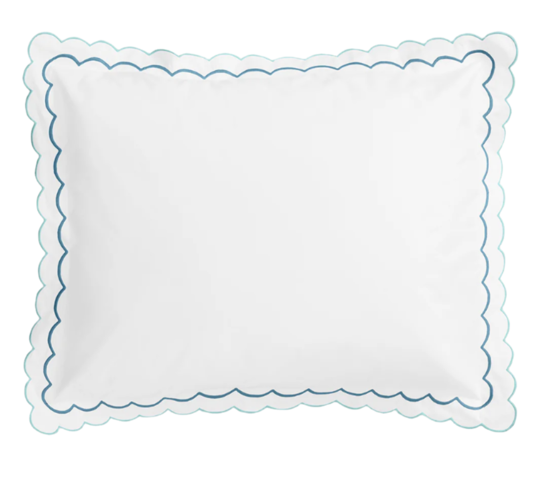 The India Bedding Collection, Cerulean by Matouk features a white rectangular pillow in soft cotton percale, with scalloped edges, delicate embroidery, and a blue wavy border design.